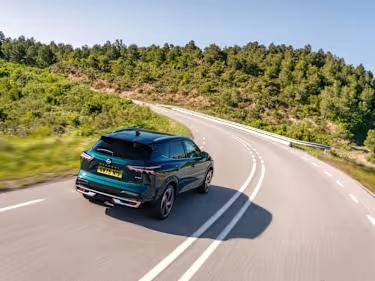 Nissan Qashqai car driving down a country road surrounded by trees