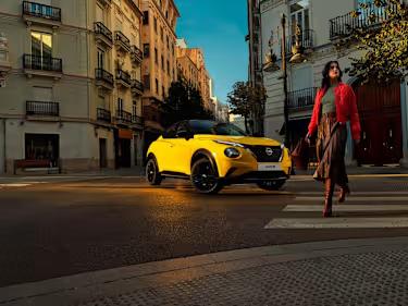 Nissan Juke car in yellow parked in the city with a woman walking in front