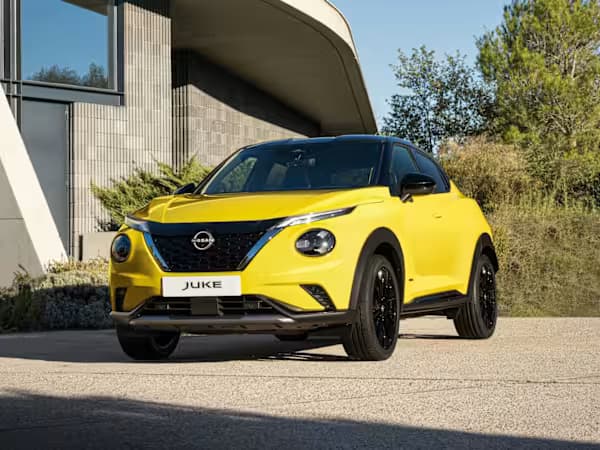 Yellow Nissan JUKE SUV parked in front of a building