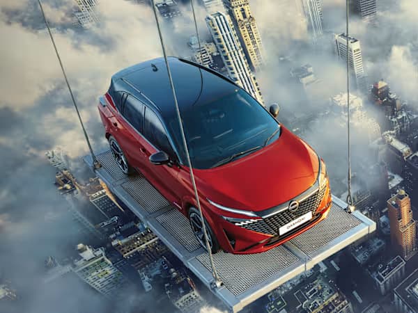 Nissan Qashqai e-Power SUV in red being lifted up above the city and clouds